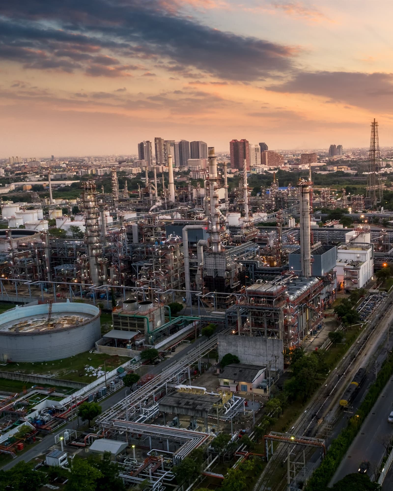 Refinery infrastructure at dusk with stacks and process units