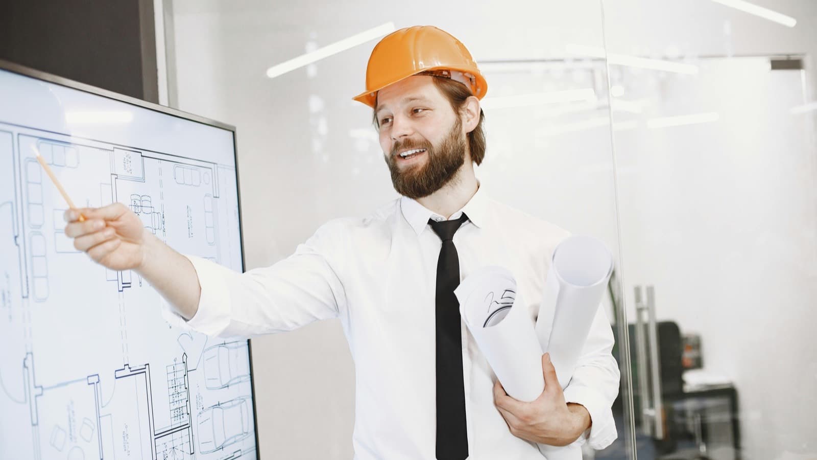 Engineer in hardhat presenting technical plans at a whiteboard during a training session